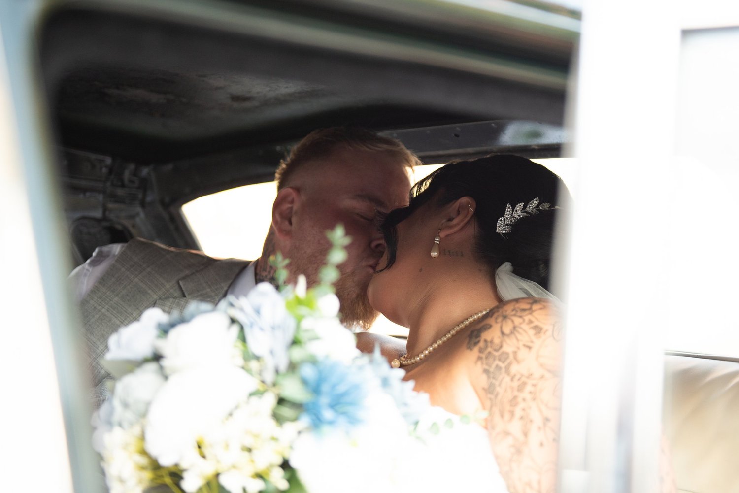 Newlyweds sharing a kiss in a wedding car
